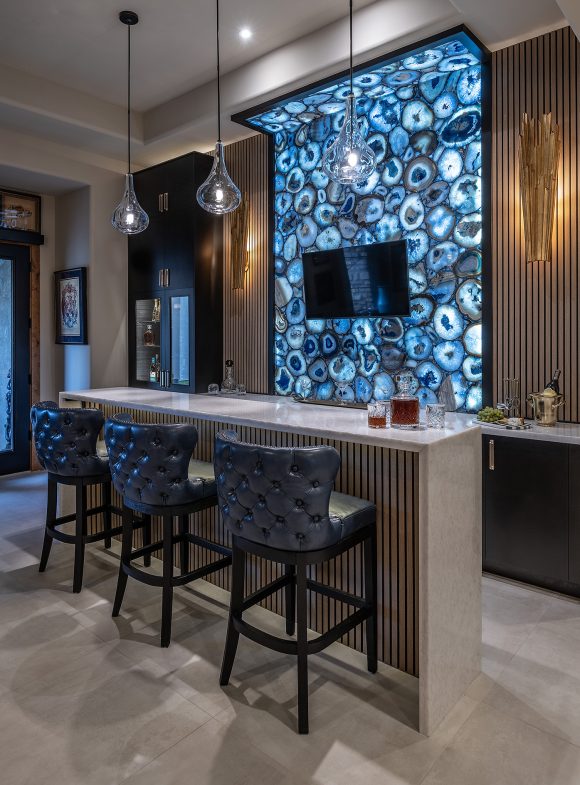 DSC_2185-1 Bar with backlit wall design, mounted T.V., three leather barstools at island and hanging lights.