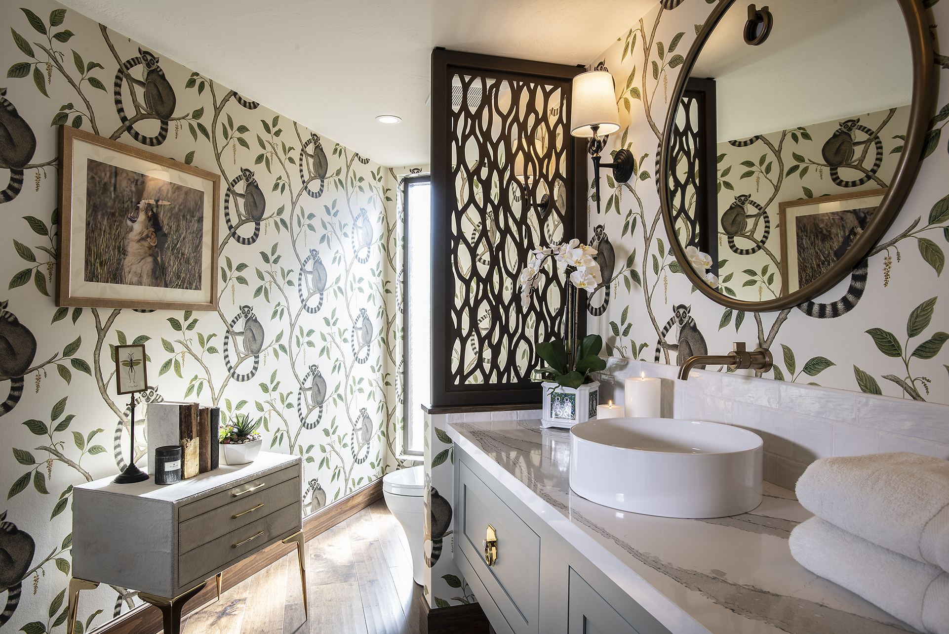 Scottsdale powder room design with exotic wallpaper, neutral white and gray colored vanity with large, round mirror.